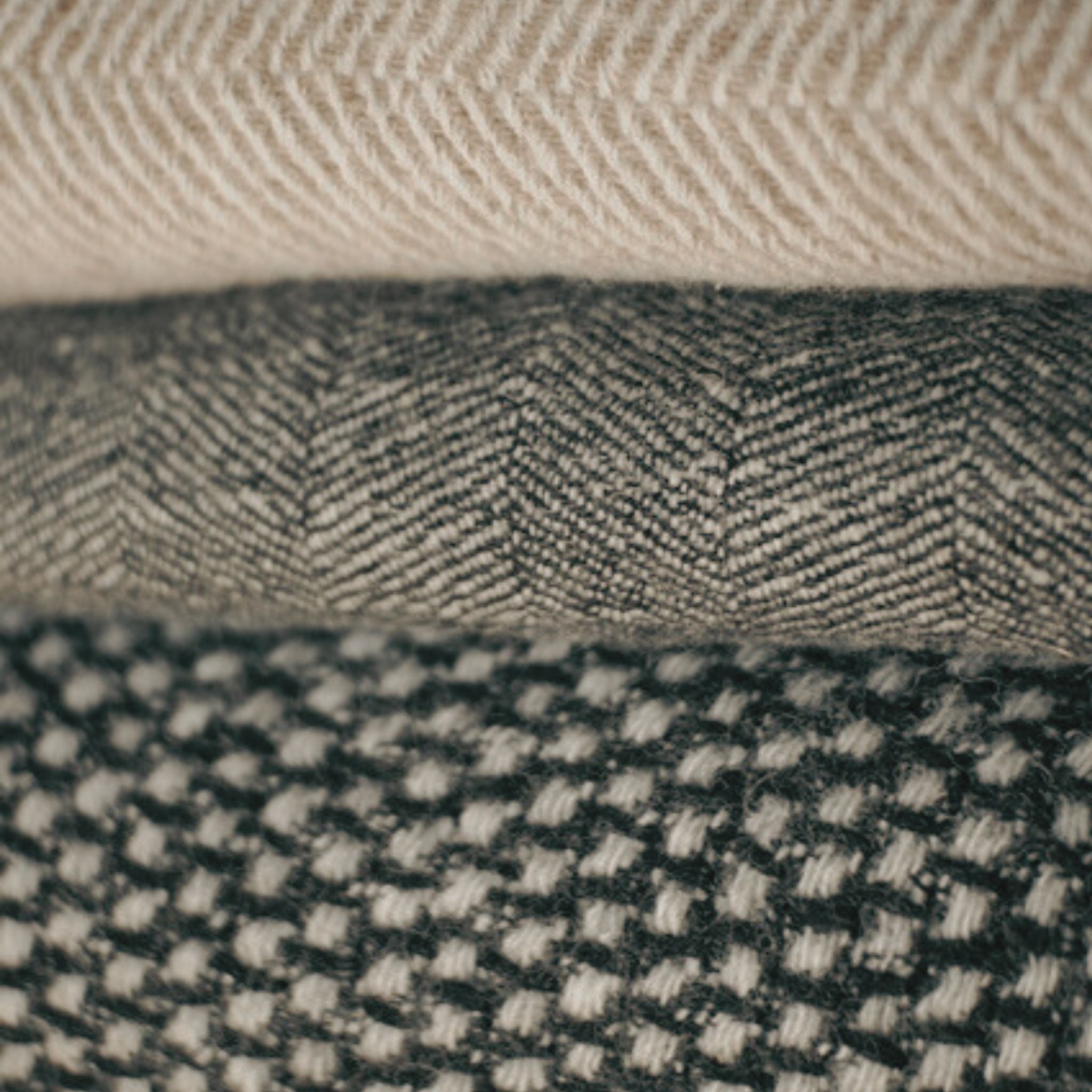 A collection of responsibly made Finnish wool throws in beige, grey, and natural shades, crafted in Finland.