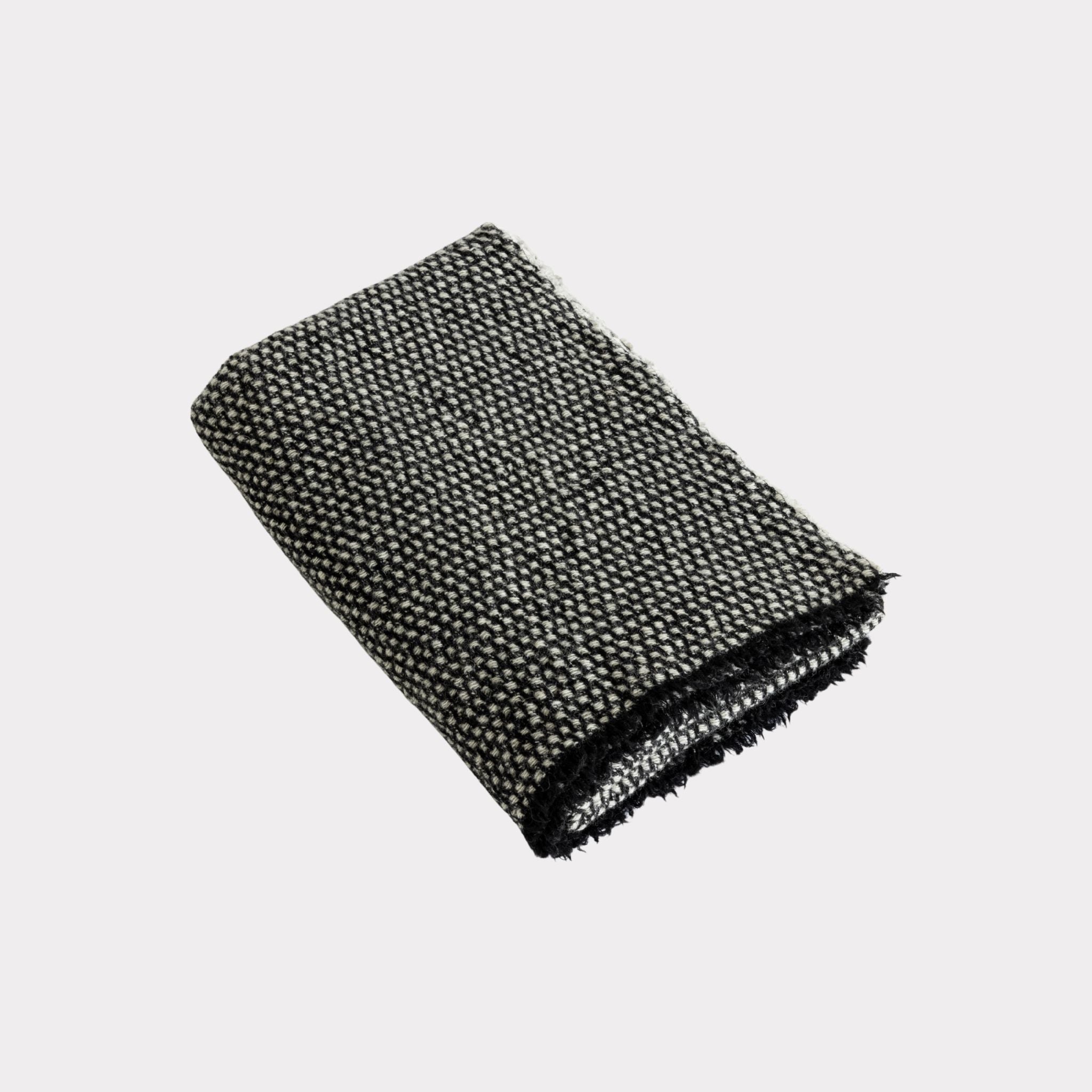 Textured white and black throw made from responsibly sourced sheep wool, manufactured in Finland.